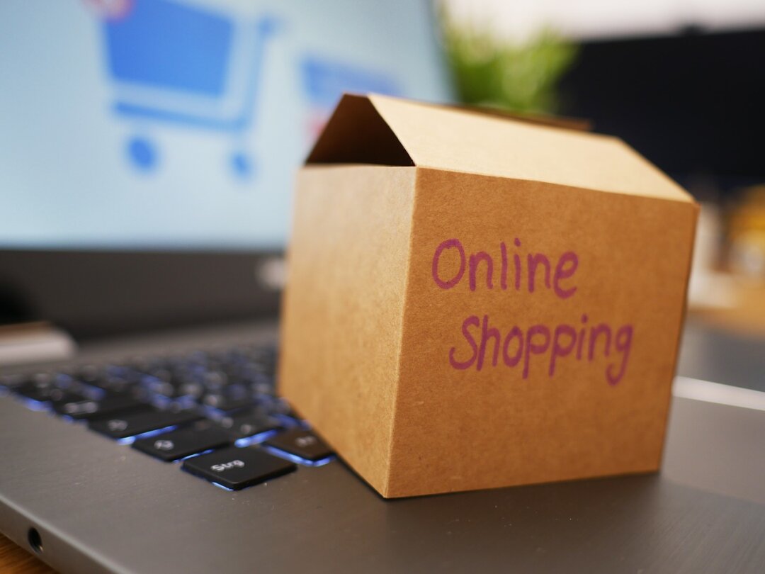 Eine kleine Pappschachtel mit dem Schriftzug Online shopping, die auf der Tastatur eines Laptops steht.